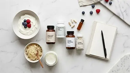 Flat lay of probiotic capsules and bottles arranged with yogurt, kefir, sauerkraut, and fresh berries for gut health.